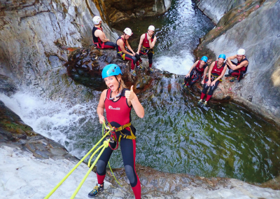 Woman rappelling down 5 metre high wall of dam in Guadalmina canyon.