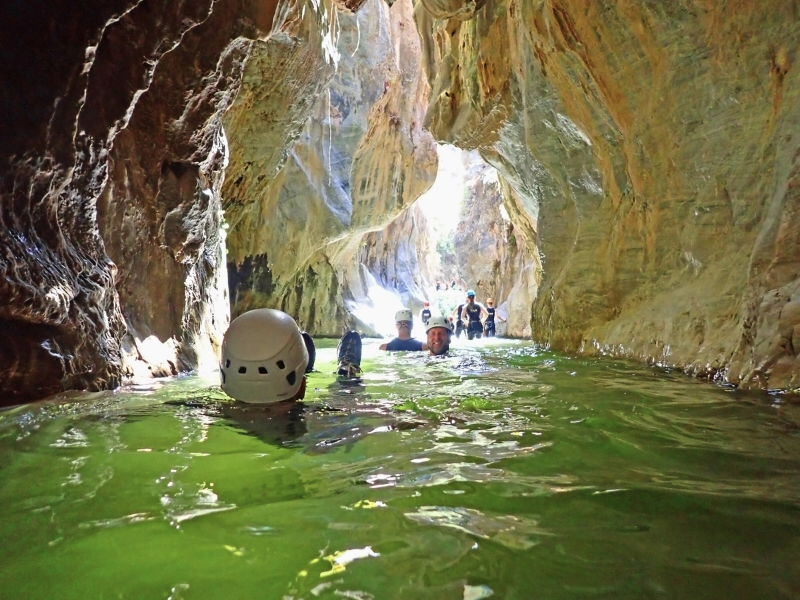 People swimming through the narrowest part of Guadalmina Canyon, surrounded by beautiful rock formations.