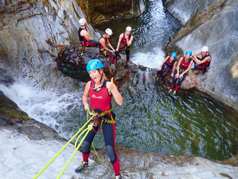 Woman rappelling down 5 metre high wall of dam in Guadalmina canyon