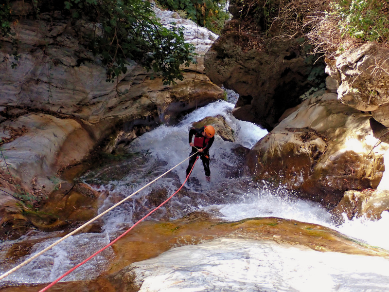 Man rappelling on a waterfall on Zarzalones Canyon