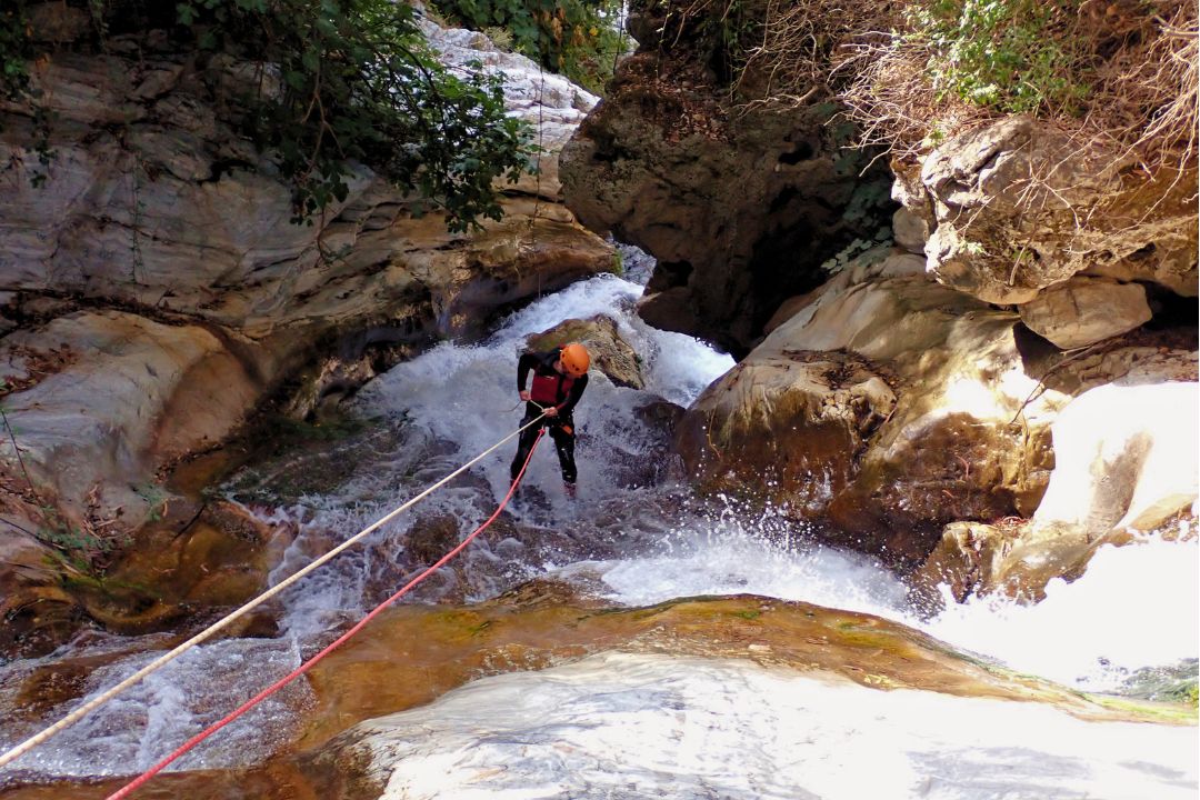 Man rappelling on a waterfall on Zarzalones Canyon.